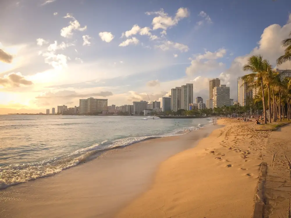 Waikiki beach at sunset with Diamond Head in the distance and surfers offshore