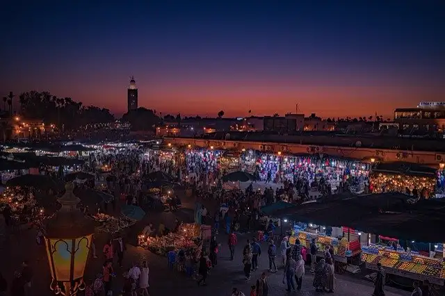 A Marrakech riad courtyard with orange trees, a tiled fountain and three storeys of zellige